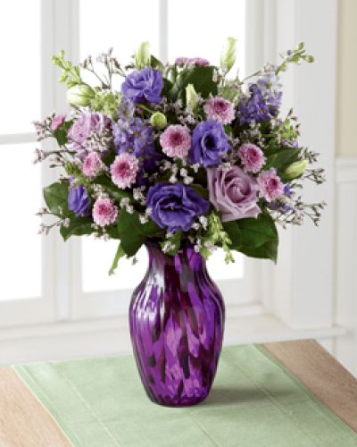 <p>Elegant and chic, this flower bouquet is laced in lavender to send your love, kindness, and gratitude to your recipient this spring season. Lavender roses and purple double lisianthus flaunt their twilight inspired beauty, mingling amongst purple button poms, purple larkspur, pink limonium, and lush greens, presented in a purple swirled glass vase. The perfect thank you, birthday, or Mother's Day gift.</p>