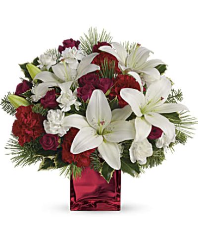 <p>Filled with holiday charm. Red spray roses and white asiatic lilies are arranged to perfection in our red mirrored cube.<br />
Red spray roses, white asiatic lilies and red carnations are accented by tips of white pine, noble fir and holly.<br />
Delivered in a beautiful red or clear cube.</p>