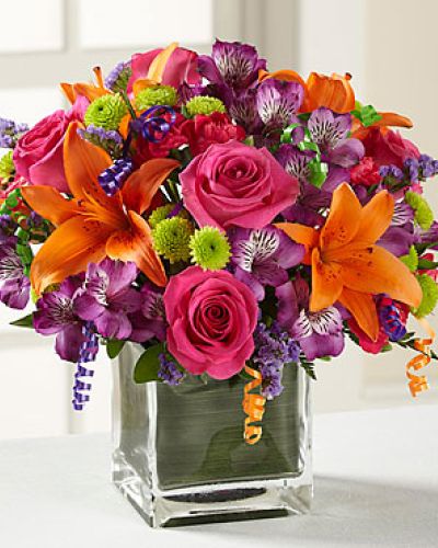 Birthday blooms that are ready to get your recipient's special day started, this flower bouquet is bright, happy, and ready to celebrate! Hot pink roses and orange Asiatic Lilies are vibrant and fun surrounded by purple Peruvian Lilies, hot pink mini carnations, green button poms, purple statice, and an assortment of lush greens. Accented with assorted curling ribbons to give it that party feels and presented in a clear glass cubed vase lined with ti leaf green material for added beauty, this unforgettable birthday bouquet is that ultimate surprise that will make them feel the love on their big day.
STANDARD bouquet includes 11 stems.
Approximately 10H x 10W.
C Quantity Color Description
2 Hot Pink 50 cm Standard Rose
1 Orange Asiatic Lily
3 Purple Alstroemeria
2 Green Button Pom
2 Hot Pink Miniature Carnation
1 Purple Filler - Sinuata Statice
2 Green Green - Leather Leaf
1 Green Green - Pittosporum
0.33 Green Green Flexible Leaf Material
1.5 Curling Ribbon (yds.)
0.33 Green Florist Foam Brick
DELUXE bouquet includes 15 stems.
Approximately 11H x 11W.
C Quantity Color Description
4 Hot Pink 50 cm Standard Rose
1 Orange Asiatic Lily
3 Purple Alstroemeria
2 Green Button Pom
3 Hot Pink Miniature Carnation
2 Purple Filler - Sinuata Statice
2 Green Green - Leather Leaf
1 Green Green - Pittosporum
0.33 Green Green Flexible Leaf Material
1.5 Curling Ribbon (yds.)
0.33 Green Florist Foam Brick
PREMIUM bouquet includes 19 stems.
Approximately 12H x 12W.
C Quantity Color Description
5 Hot Pink 50 cm Standard Rose
2 Orange Asiatic Lily
4 Purple Alstroemeria
3 Green Button Pom
3 Hot Pink Miniature Carnation
2 Purple Filler - Sinuata Statice
2 Green Green - Leather Leaf
1 Green Green - Pittosporum
0.66 Green Green Flexible Leaf Material
3 Curling Ribbon (yds.)
0.5 Green Florist Foam Brick